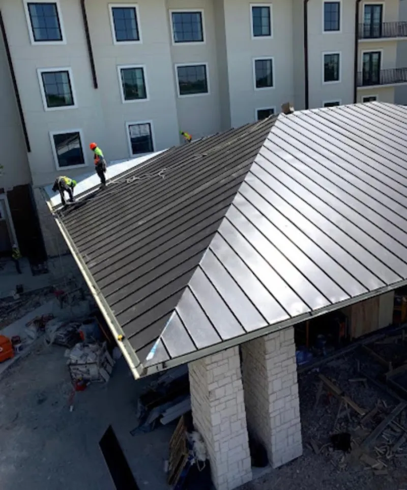 Crew installing standing seam metal roof panels on a commercial project in Parlier